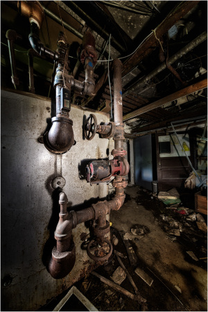Rusty pipes intertwine in a shadowy realm, hinting at forgotten stories.