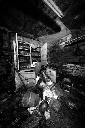 A shadowy chamber filled with scattered debris and forgotten relics of the past.