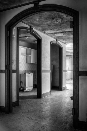 Interior of an old building with arched doorways and a visible kitchen area