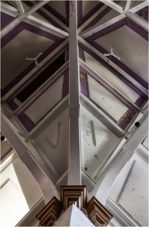 Intricate wooden beams converge in a dance of angles and shadows, painted in muted hues.