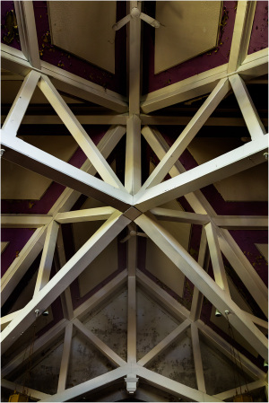 Intricate wooden beams form a star pattern against a muted backdrop.