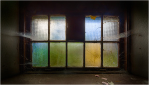 A stained glass window with colorful panes and a hint of nature outside.
