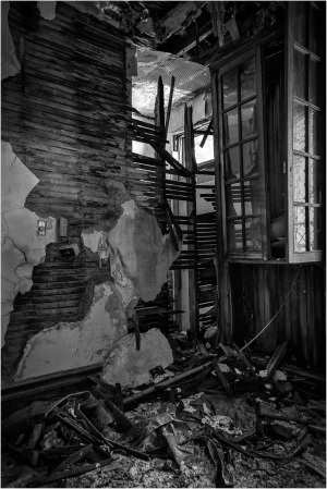 A chaotic mess of broken wood and shattered walls in a dimly lit room, echoes of better days lost.