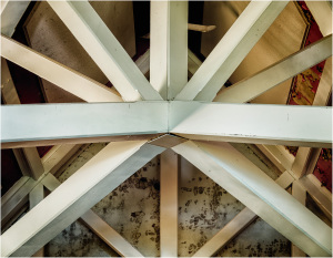 Intricate wooden beams crisscrossing in a ceiling design, showcasing craftsmanship and age.