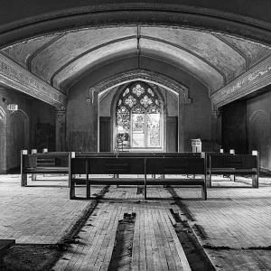 Interior of a historic building featuring a vaulted ceiling and stained glass window.