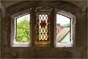 Three arched windows with a central stained glass panel featuring geometric designs.
