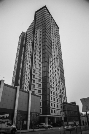 Tall residential building with glass facade and adjacent low-rise structure.