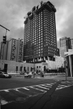 A tall building under construction in a city with a cloudy sky and street intersection.
