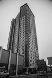 Tall residential building with glass facade and adjacent low-rise structure.