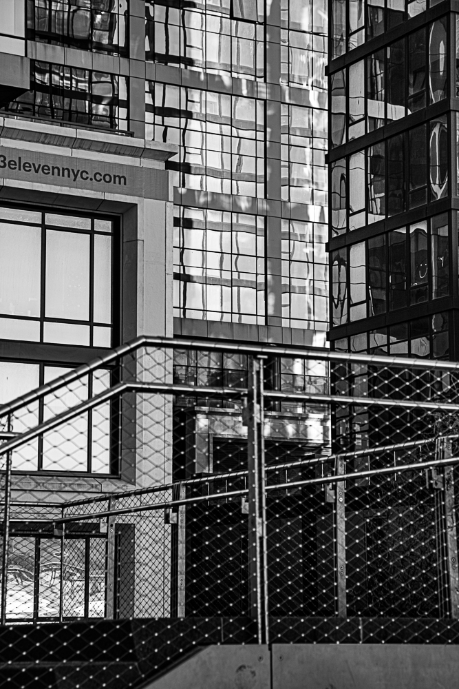 A modern urban scene featuring glass buildings and a metal railing.