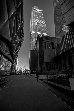 A narrow urban pathway flanked by tall, modern buildings in black and white.