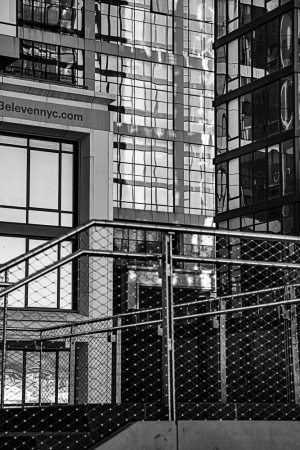 A modern urban scene featuring glass buildings and a metal railing.
