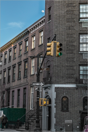 Street corner in NYC with a traffic light and historic buildings under a clear sky.