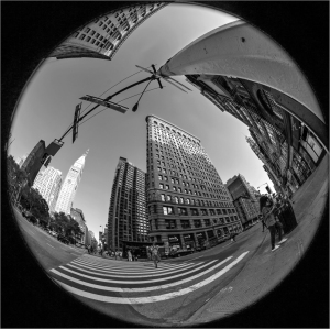 A fisheye view of a city street with tall buildings and a crosswalk.