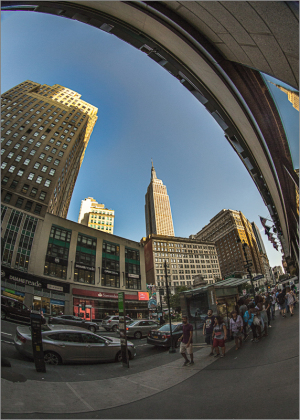 View of a busy street in NYC with tall buildings and the Empire State Building in the background.