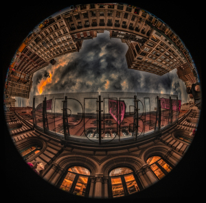 A fisheye view of a cityscape with buildings and a dramatic sky.