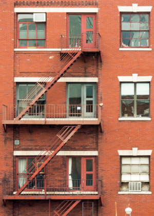 Red brick building with fire escape and multiple windows in New York City.
