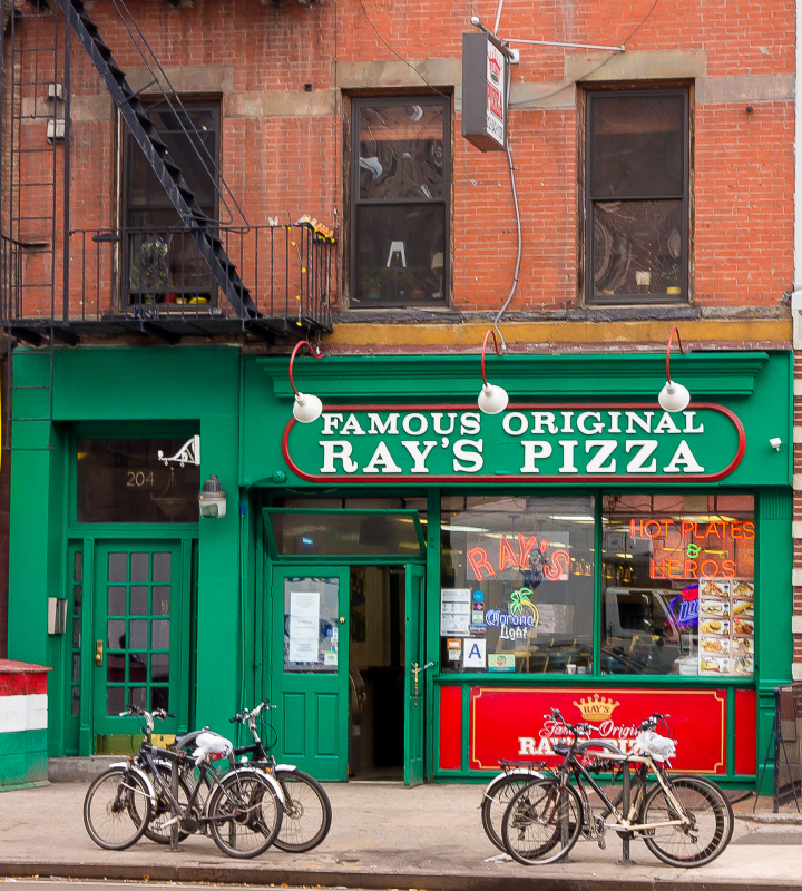 Exterior of Ray's Pizza with green facade and bicycles parked outside.