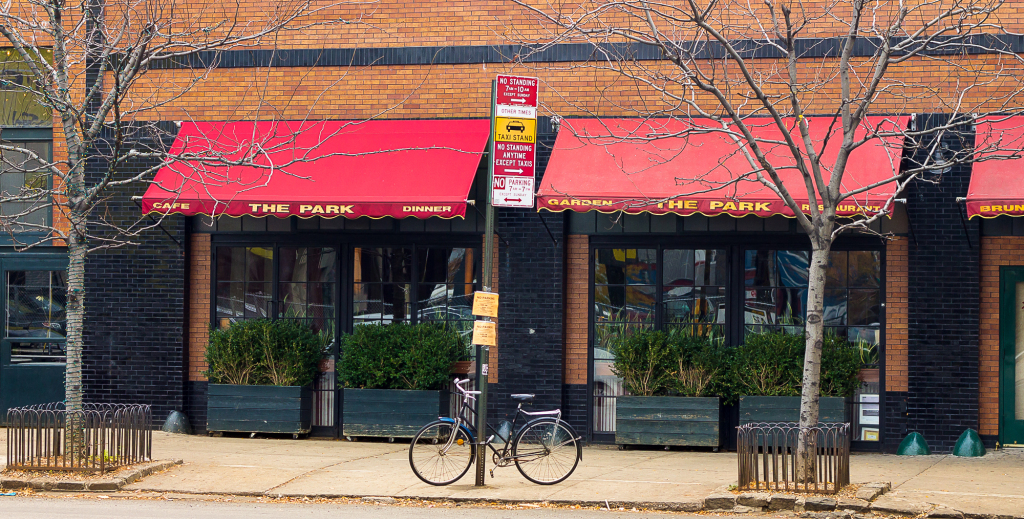 A restaurant with red awnings and a bicycle parked outside.