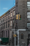 Street corner in NYC with a traffic light and historic buildings under a clear sky.