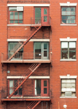 Red brick building with fire escape and multiple windows in New York City.