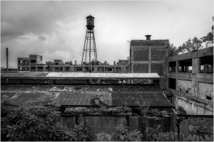 A decaying industrial landscape with a water tower looming over crumbling buildings.