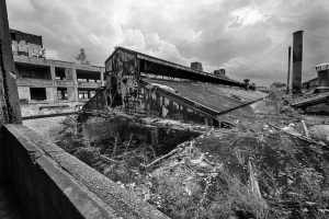 A dilapidated industrial building surrounded by debris under a moody sky.