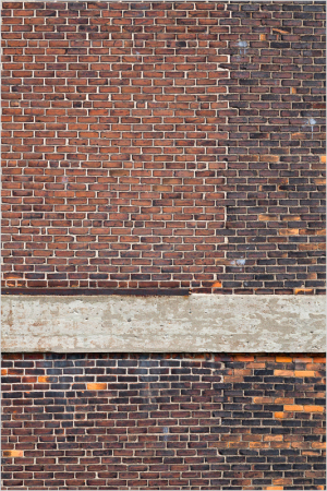A textured wall of aged bricks in deep reds and browns, with a weathered wooden beam across the center.