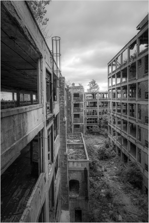 Abandoned industrial buildings with broken windows and overgrown vegetation