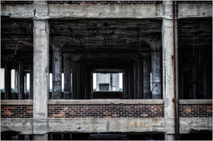 A view through the skeletal remains of a building, showcasing concrete and brick structures.