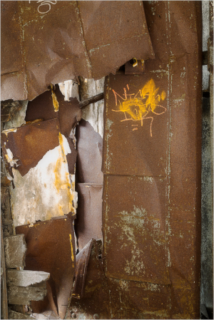 Close-up of rusted metal sheets with peeling paint and graffiti.