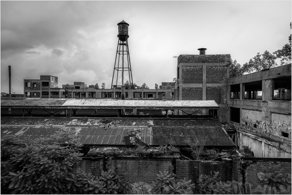 A decaying industrial landscape with a water tower looming over crumbling buildings.