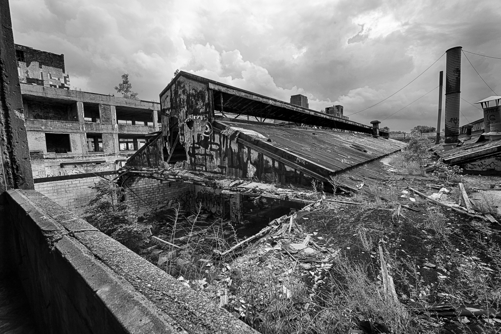 A dilapidated industrial building surrounded by debris under a moody sky.