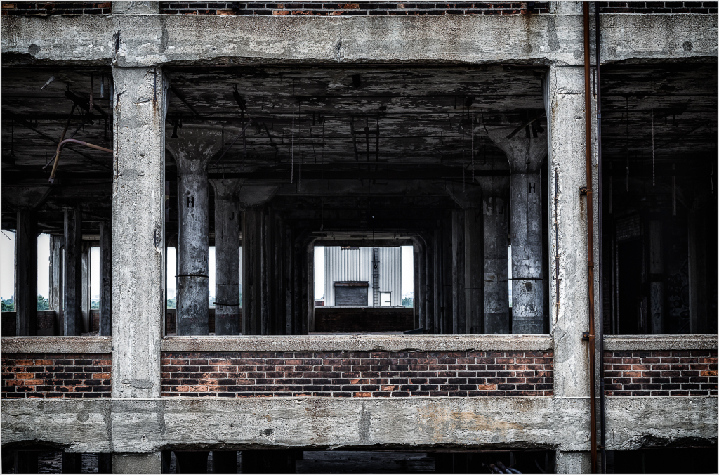 A view through the skeletal remains of a building, showcasing concrete and brick structures.