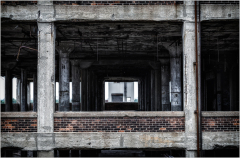 A view through the skeletal remains of a building, showcasing concrete and brick structures.