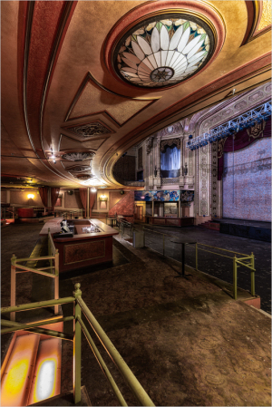 An ornate theater interior, empty, with grand ceilings and muted light.