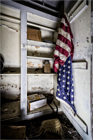An old closet with a faded American flag and empty shelves, hinting at forgotten history.