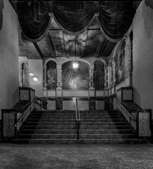 Interior of the Paramount Theatre, showcasing grand stairs and faded murals.