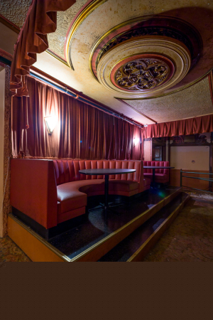 A cozy, forgotten seating area in the Paramount Theatre with rich red curtains and ornate ceiling.
