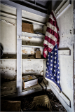 An old closet with a faded American flag and empty shelves, hinting at forgotten history.