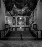 Interior of the Paramount Theatre, showcasing grand stairs and faded murals.