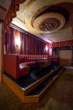 A cozy, forgotten seating area in the Paramount Theatre with rich red curtains and ornate ceiling.