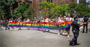 Marchers hold a colorful banner reading 'Gays Against Guns' at Pride Day in NYC.