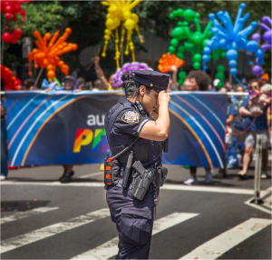 Police officer at Pride Day NYC, vibrant colors and balloons in the background.