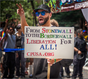 Person at NYC Pride Day holds sign advocating for liberation and equality.