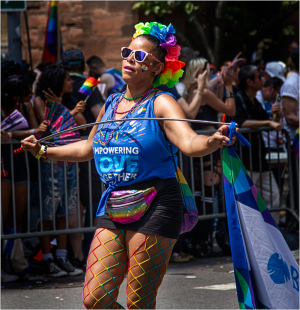 A vibrant parade participant in colorful attire celebrates with joy and pride.