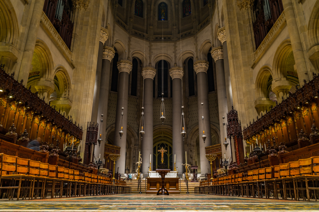 A grand cathedral interior with towering columns and intricate wooden pews.
