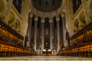 A grand cathedral interior with towering columns and intricate wooden pews.