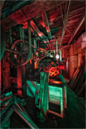 An abandoned mill's machinery shrouded in eerie red and green light; haunting remnants linger.