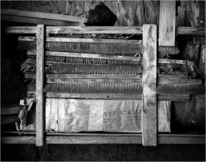 Weathered wooden shelves filled with forgotten tools and dust-covered materials.